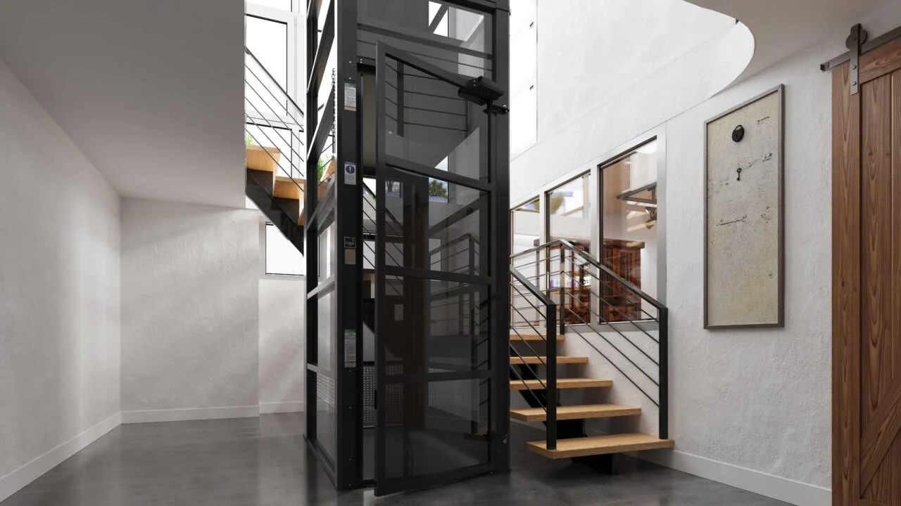 Black framed home elevator with glass walls installed beside a staircase in a modern entryway