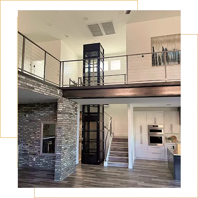 Home elevator installed in open two story living space with kitchen and stone wall