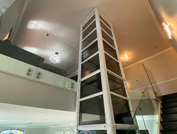 Cube pneumatic home elevator installed in a modern two story living space with glass railings