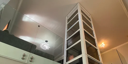Cube pneumatic home elevator shaft framed in white rising through a two story interior