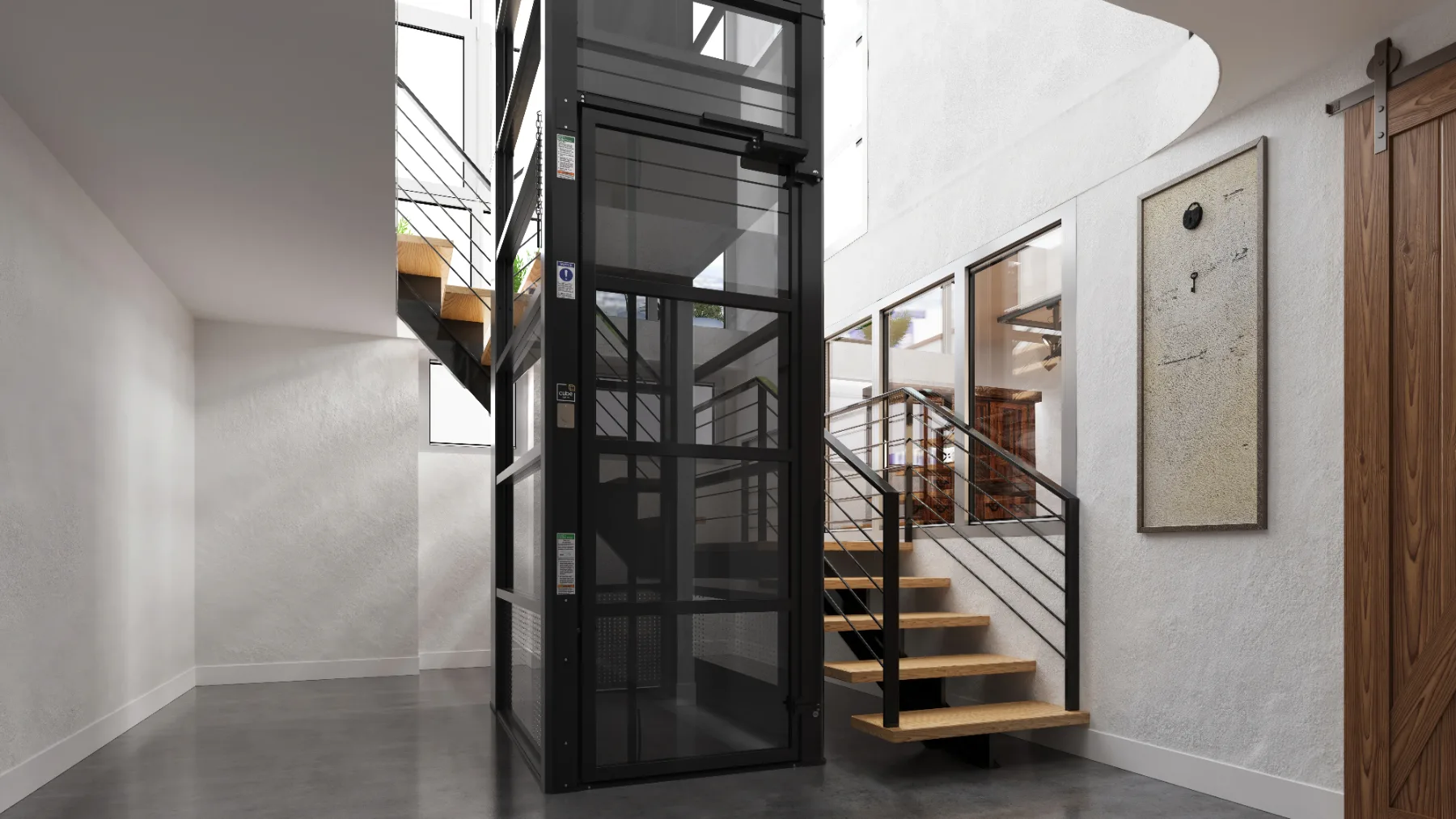 Black framed home elevator beside a staircase in a modern open foyer